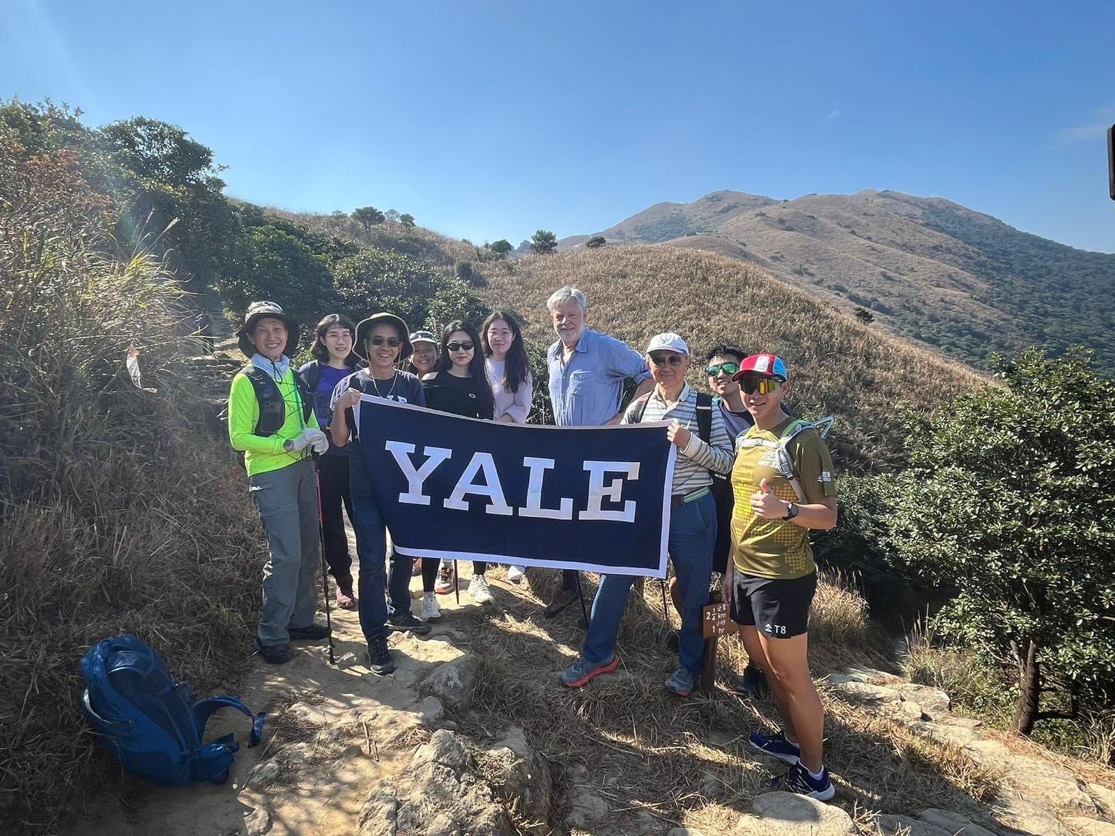 Club members holding a Yale banner on the trail up Sunset Peak